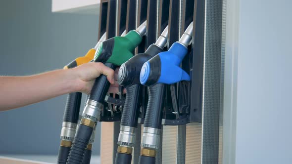 A Person Puts a Gas Nozzle Back Into the Fuel Pump