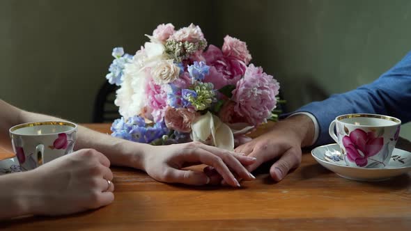 Closeup of Bride Stroking Hand of Groom in Cafe