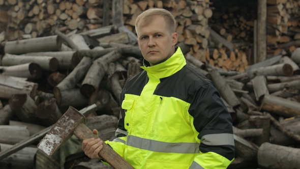 Lumberjack in Reflective Jacket. Man Woodcutter Hold Huge Axe. Sawn Logs, Firewood Background