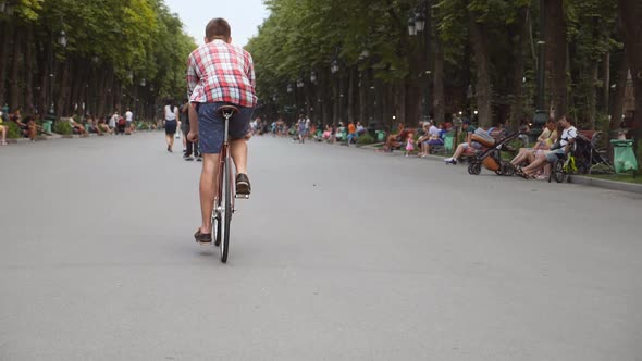 Young Man Riding a Vintage Bicycle at the Park Alley