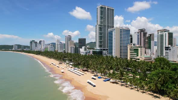 wide aerial view  of an asian beach town on a sunny day as ocean waves crash onto the prestine and e