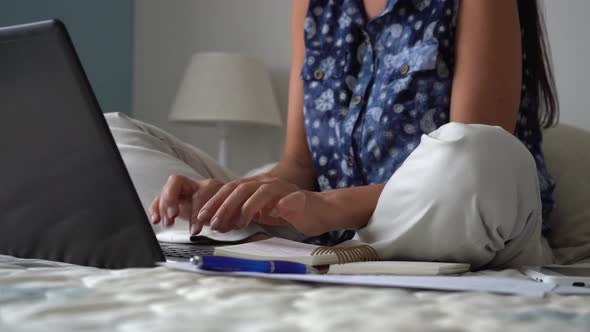 Caucasian woman working from home on bed typing on laptop, covid-19