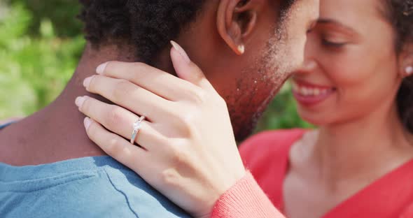 Close up of happy biracial woman with engagement ring on hand hugging to fiance