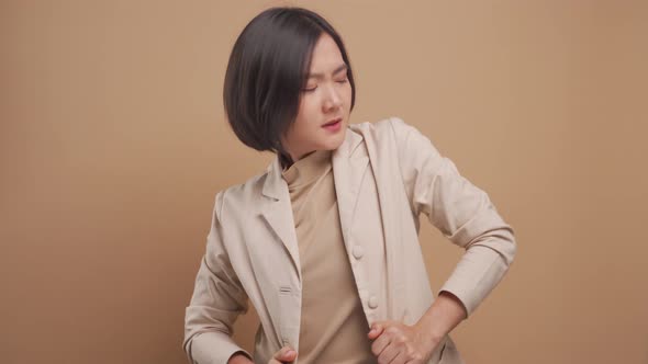 Asian business woman was sick with body pain and standing isolated over beige background. 4K video