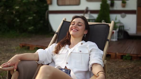 Pleased Attractive Caucasian Woman Chilling Out and Smiling While Laying on Lounger Outdoors