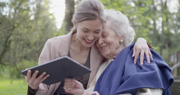 Woman and Senior Grandmother Using Tablet Device for Video Call at Park