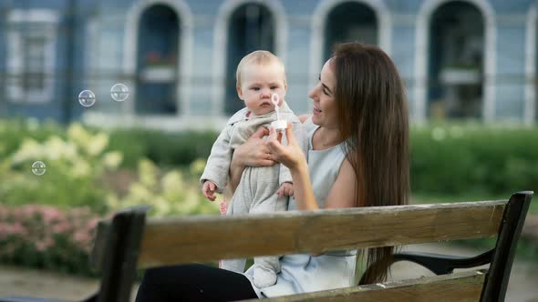 Mother and Her Baby Daughter Playing with Blowing Bubbles in the Garden