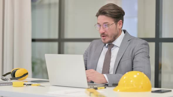 Middle Aged Engineer Celebrating Success while using Laptop in Office