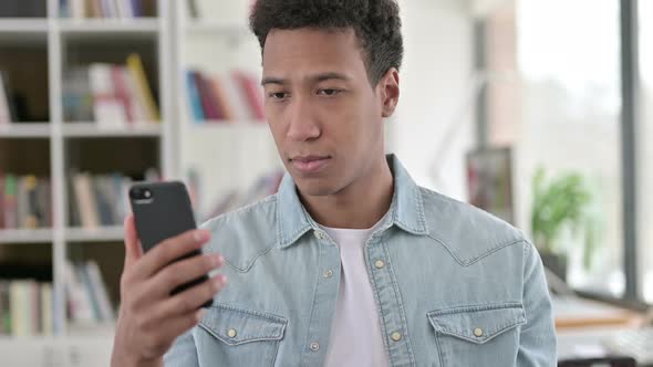 Young African American Man Disappointed By Loss on Smartphone 