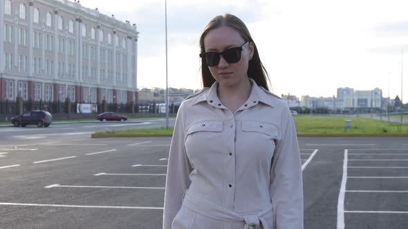 Beautiful Young Girl with Glasses Walks Through the City and Looks Around