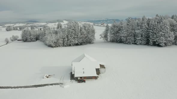 Jib up of small farmhouse standing in snow covered landscape