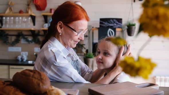 Closeup of a Loving Elderly Grandmother Kissing Her Little Granddaughter 7 Years Old on the Head