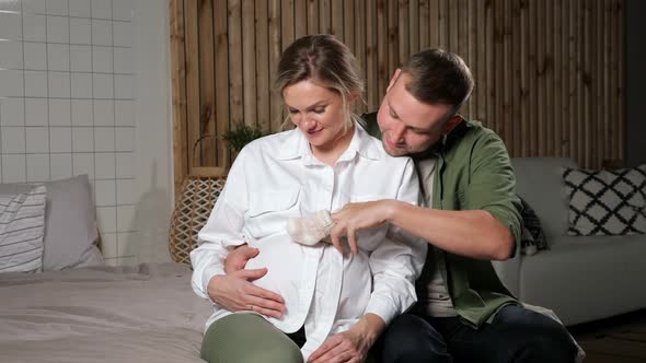 Man Hand Steps Fingers with Socks Across Pregnant Lady Belly