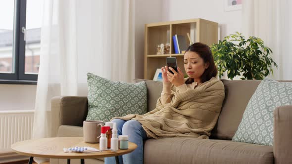 Sad Sick Woman in Blanket Using Smartphone at Home