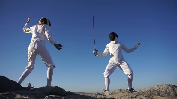 A man and woman fencing on the beach
