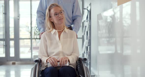 Close Up of Beautiful Mature Woman Smiling Sitting in Wheelchair with Husband Pushing It