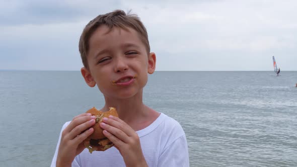A Little Boy Bites a Hamburger