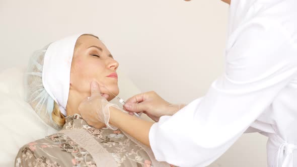 Doctor Inserts a Needle Into a Woman's Face Subcutaneously Closeup