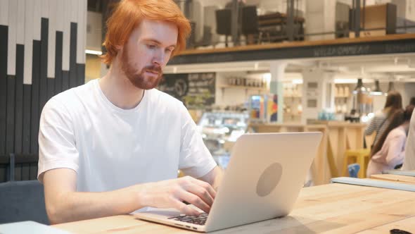 Redhead Beard Man Working on Laptop in Cafe, Coworking
