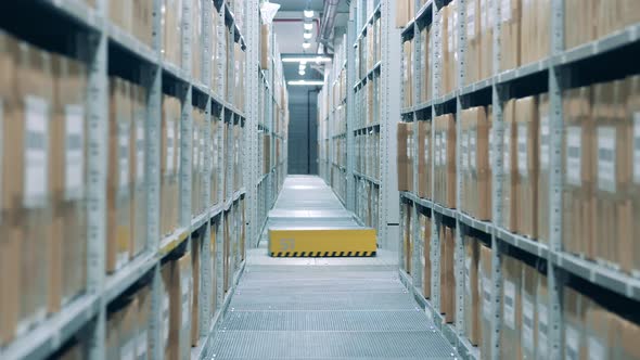 Automated Warehouse Robot is Riding Past a Corridor