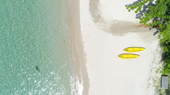 Wide drone shot of two yellow kayaks on the beach. Koh Kood, Thailand.