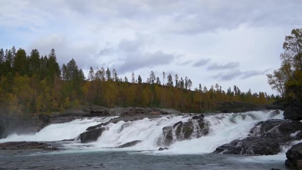 Broad Waterfall in Northern Norway in Autumn with Rocks and Water Foam