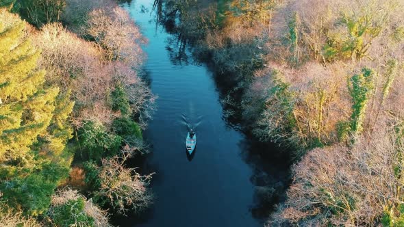 Aerial shot boat driving along river in Autumn