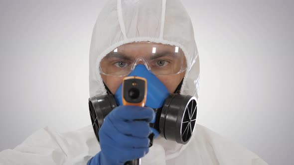 Doctor in Protective Biohazard Suit Points Laser Thermometer To Check Your Temperature at a Covid19