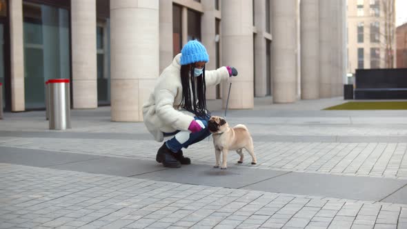 African Woman in Mask Spraying Detergent After Pet Peeing on Sidewalk Outdoors