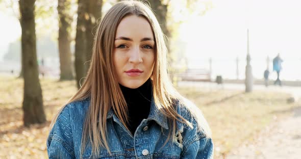 Portrait of Young Attractive Female Looking at the Camera on Autumn Park. Cheerfully Pretty Woman at