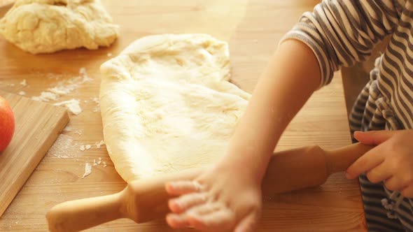 Closeup of a Little Girl's Hands Rolling Out Dough for Making Cookies or Pizza