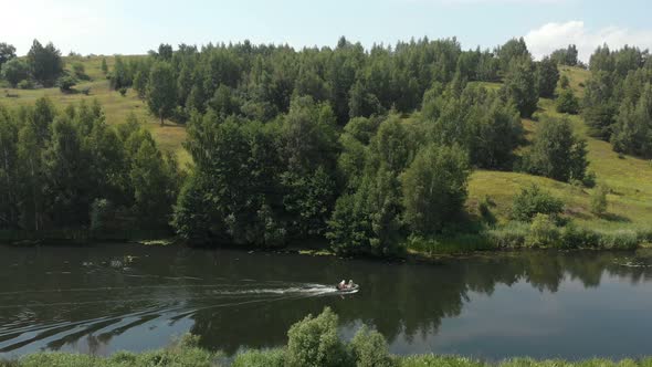 A Small Rubber Fishing Boat with A Motor Is Moving Quickly on A Small River