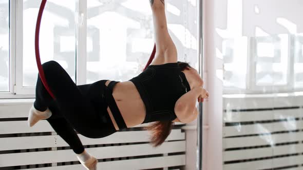 A Young Woman Gymnast Spinning Sitting on Acrobatic Ring