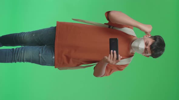 Asian Boy Student Wearing A Mask, Winning The Game On Mobile Phone While Walking On Green Screen