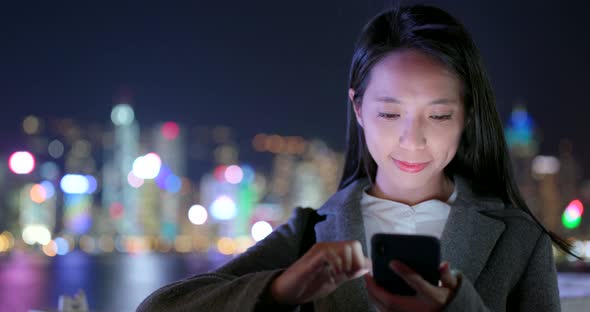 Businesswoman use of cellphone in city at night