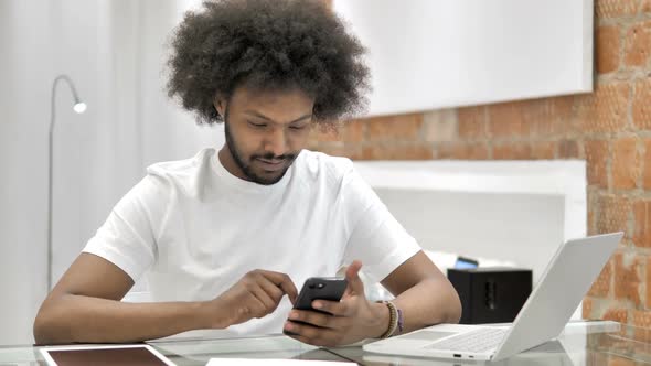 African Man Excited for Success on Smartphone