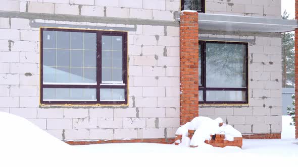 An unfinished house made of porous brick stands under the snow in winter - unfinished construction,