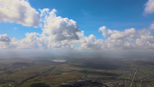 Aerial View From High Altitude of Distant City Covered with Puffy Cumulus Clouds Forming Before