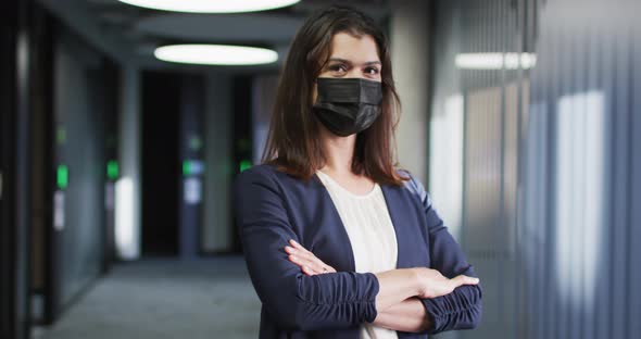 Portrait of caucasian businesswoman with brown hair wearing face mask in modern office