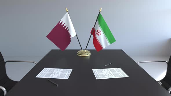 Flags of Qatar and Iran and Papers on the Table