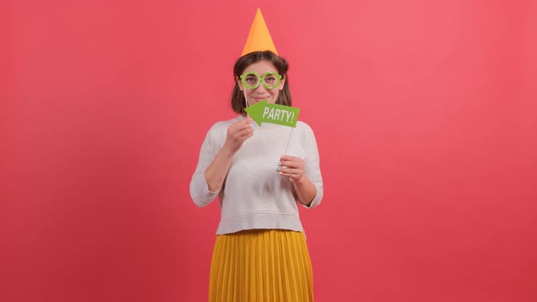 Happy Young Woman in Party Hat Holding Birthday Accessories on Red Background