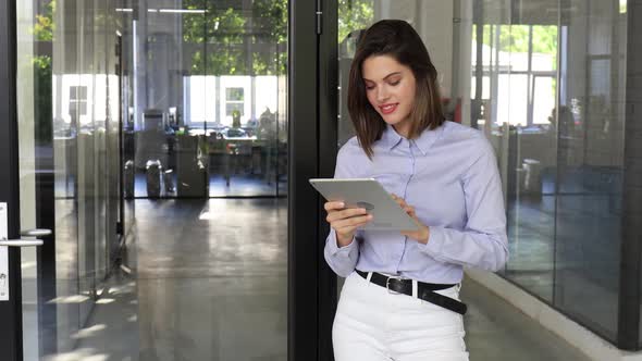 Young Attractive Smiling Caucasian Woman Using Tablet Standing at Modern Office