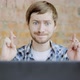 Young man in front of the laptop with his fingers crossing, Crossed fingers symbolizing good luck - VideoHive Item for Sale