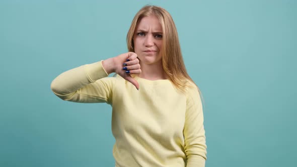 Young Girl Making a Thumbs Down Gesture Expressing Discontent, Disapprova.