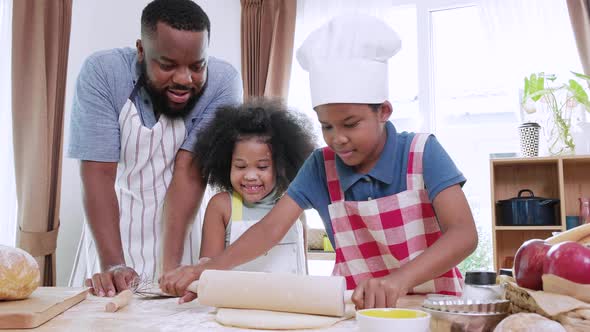 Happy mixed race family having fun in kitchen while threshing flour together for cookies at home