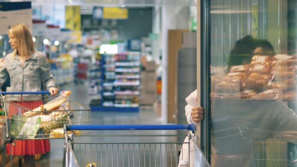 Hypermarket with Two Women Shopping for Food