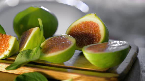 Basil leaves falling on cut green figs