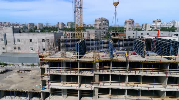 Builders are lifting a concrete bucket with a tower crane. Drone footage