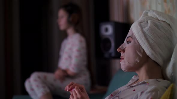 Profile Portrait, Woman in Cosmetic Fabric Mask, with White Towel on Her Head, Files Her Nails with