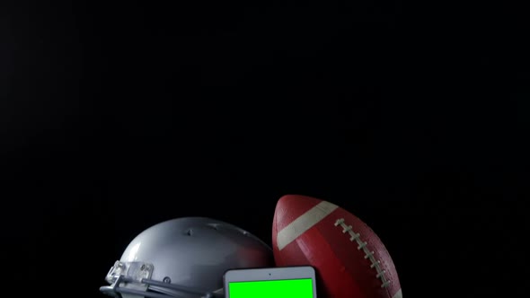 Close-up of football, mobile phone and head gear on artificial turf